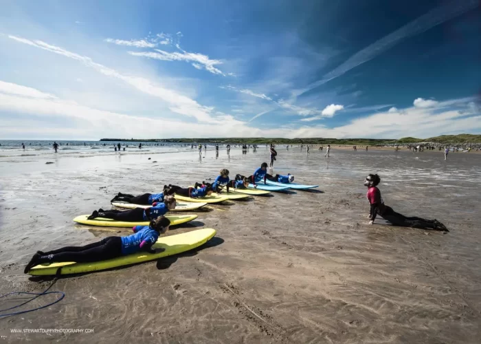 A group of surfers practicing on surfboards on the beach before entering the water.
