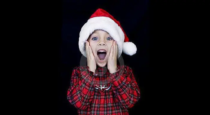 Child in santa hat expressing surprise or excitement.