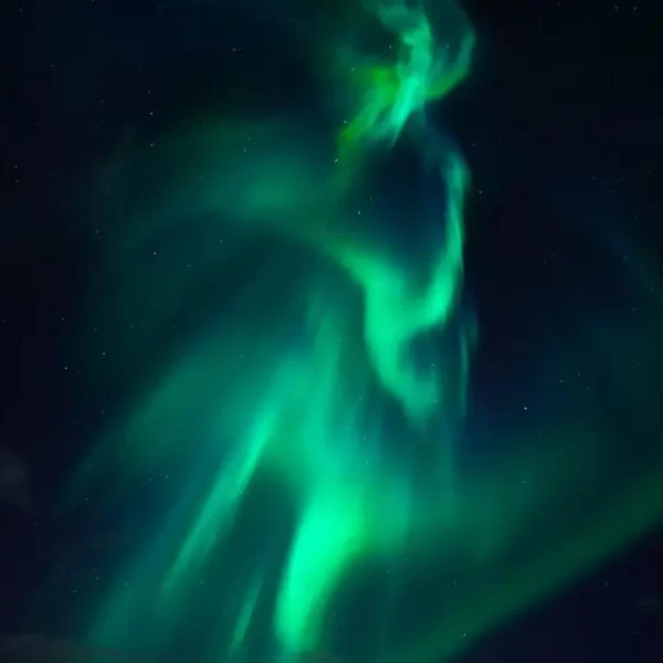 Vibrant green aurora borealis undulating in the night sky.