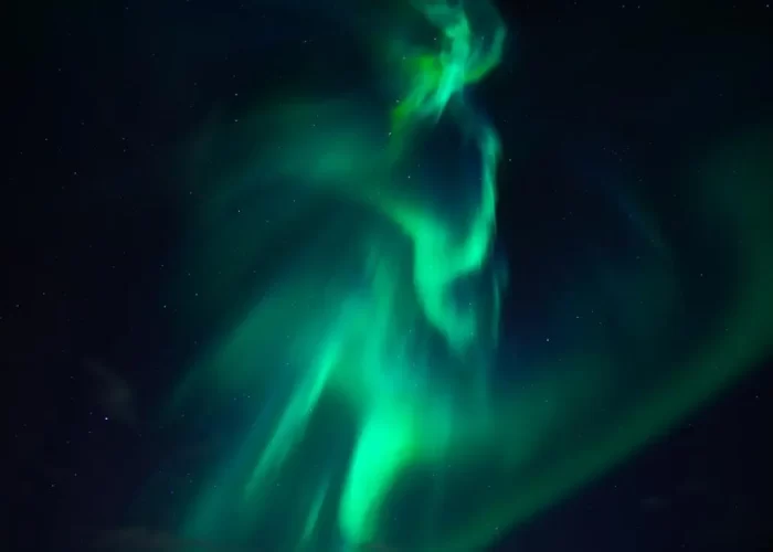 Vibrant green aurora borealis undulating in the night sky.