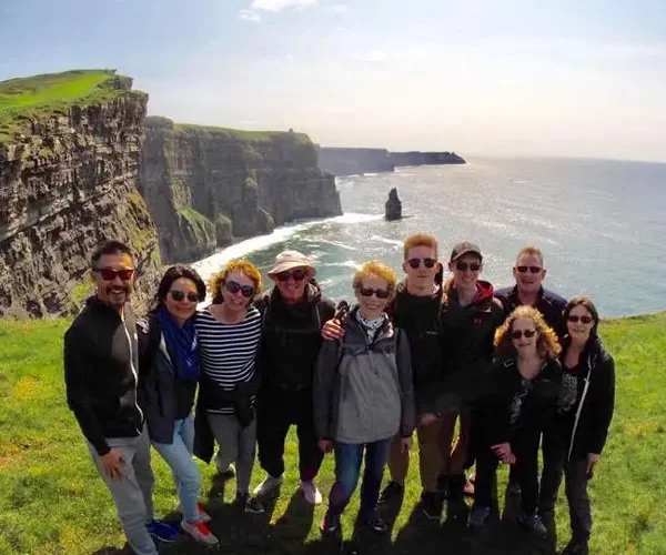 Group of tourists posing for a photo at the cliffs of moher.