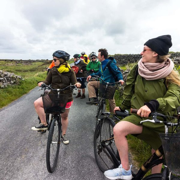 Group of cyclists on a scenic road with overcast skies.