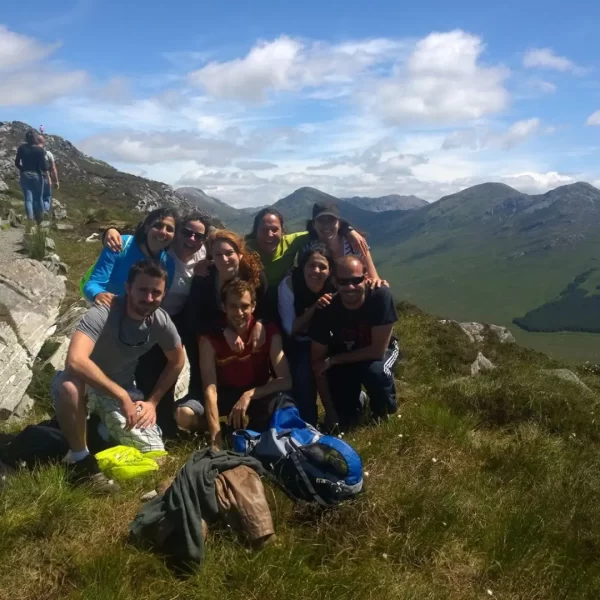 Group of hikers taking a break and posing for a photo on a sunny mountain trail.