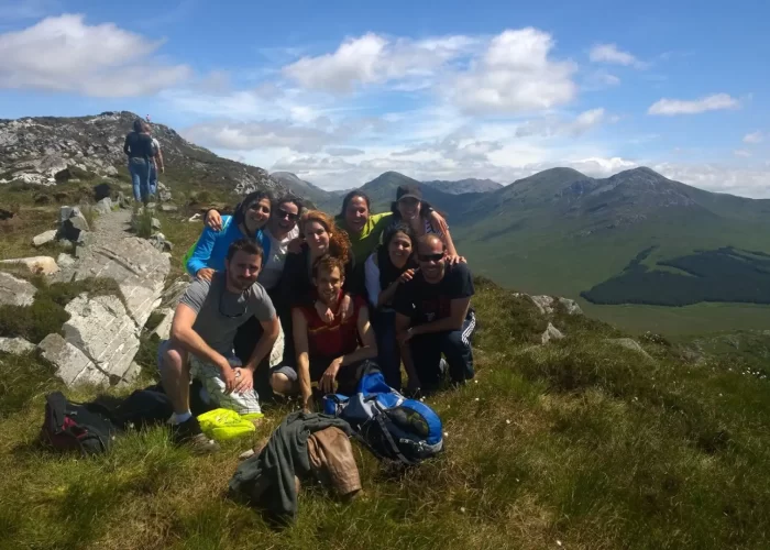 Group of hikers taking a break and posing for a photo on a sunny mountain trail.