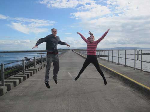a couple jumping on an Irish dock