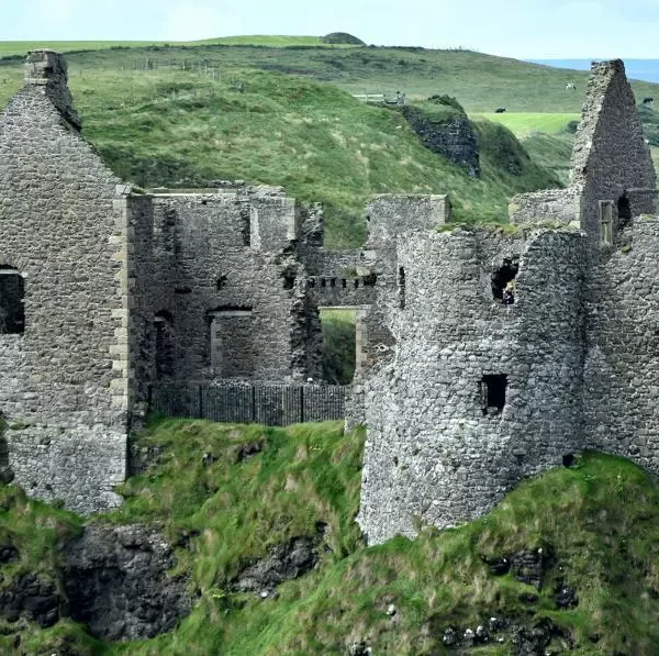 Ruins of a medieval castle on a grassy hill.