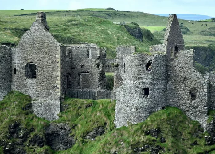 Ruins of a medieval castle on a grassy hill.
