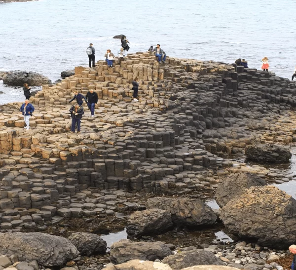 Tourists exploring the unique hexagonal rock formations at the giant's causeway in northern ireland.