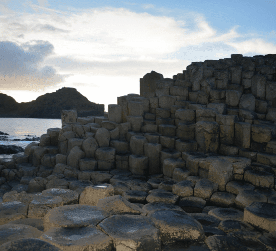 Natural hexagonal rock formations at the Giant's Causeway in Ireland during sunset, explored on private tours.