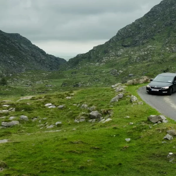 Car driving on a winding mountain road in a rocky landscape.