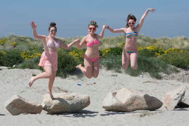 Three girls jumping on a beach in the sun in Ireland
