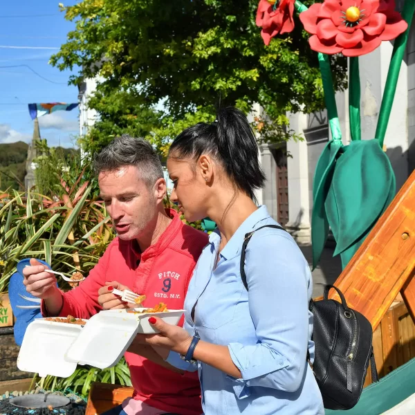 Two people enjoying a meal outdoors on a sunny day.