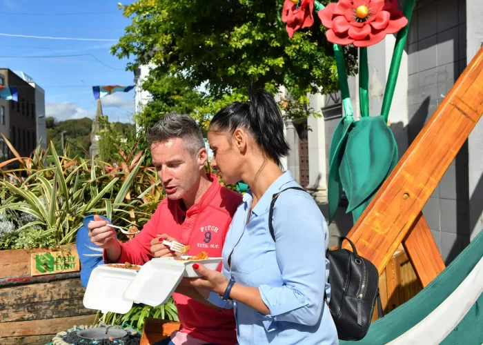 Two people enjoying a meal outdoors on a sunny day.