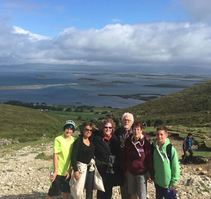 Group of hikers posing for a photo with a scenic coastal backdrop and clear blue skies on their Ireland Tours.