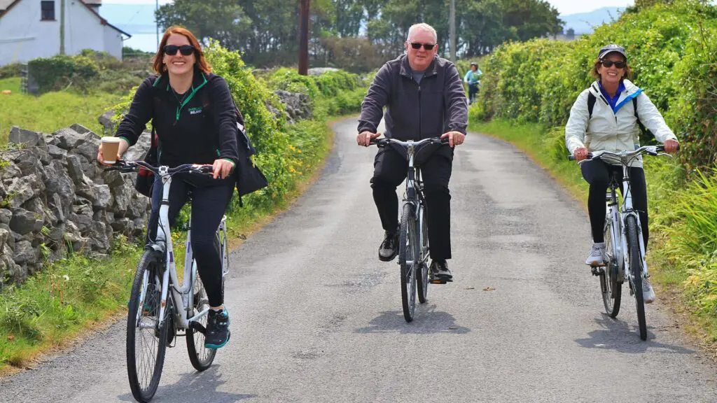 three adults on bikes trail among greenery