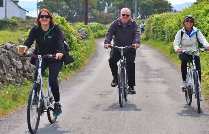 three adults on bikes trail among greenery