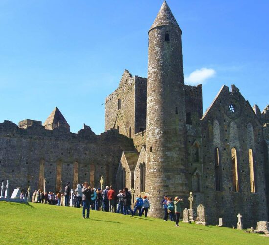 Visitors exploring the ruins of an ancient stone abbey on a sunny day during their Small Group Tours.