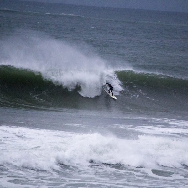 A surfer riding a large wave in a rough sea.