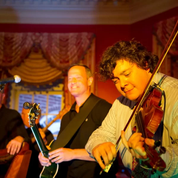 A group of musicians performing, featuring a violinist in the foreground.