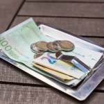 A bill with cash and coins on a tray indicating a payment or a tip left on a wooden table.