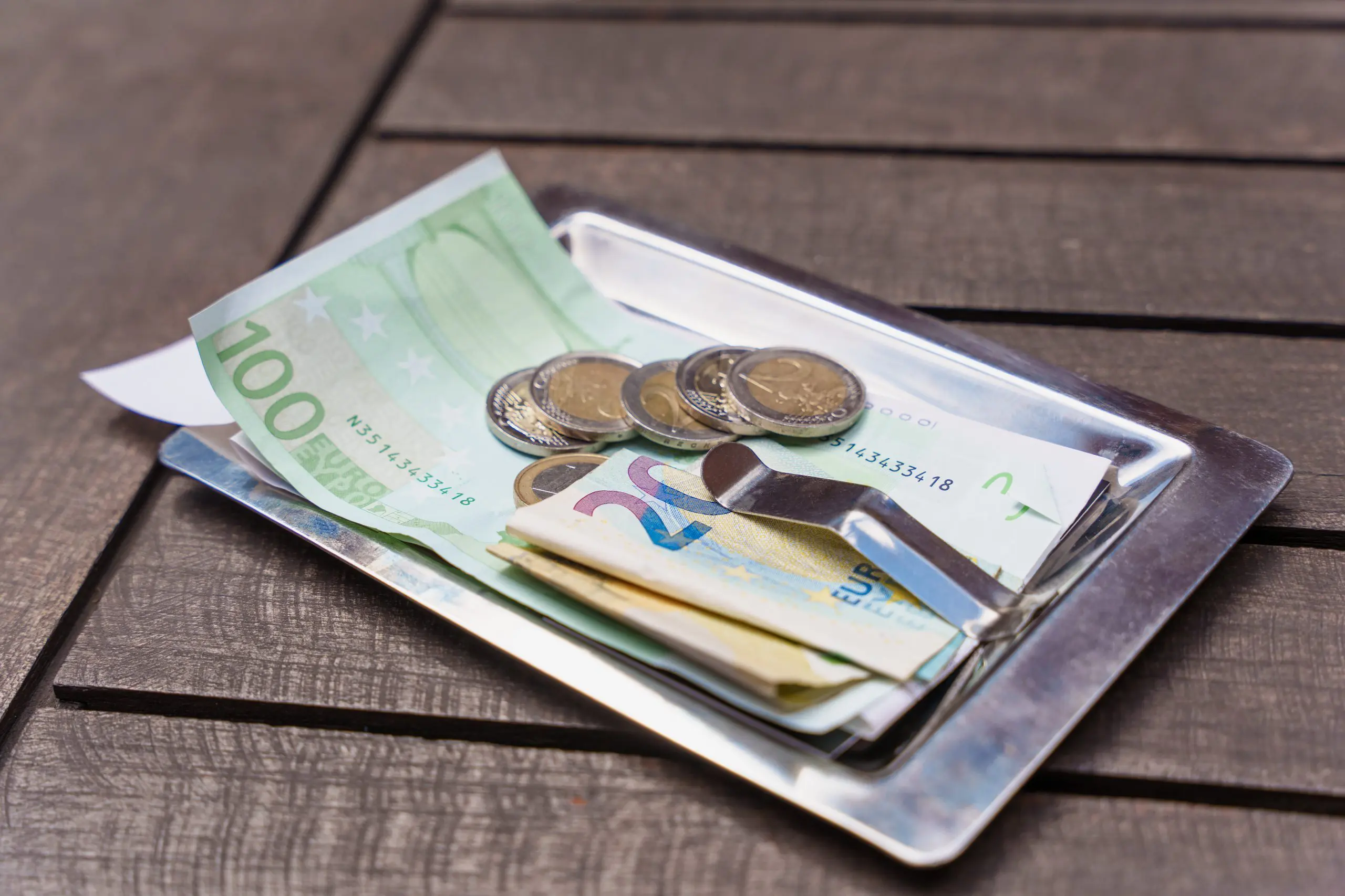 Euros arranged on a small tray, indicating a payment or tip left on a wooden table for private tours.