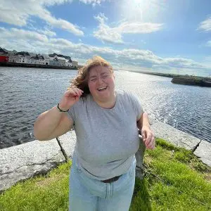 Woman laughing by the waterfront on a sunny day.