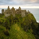 Ruins of an ancient castle perched on a cliff overlooking the sea.