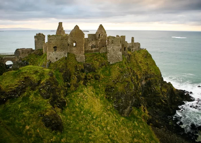 Ruins of an ancient castle perched on a cliff overlooking the sea.