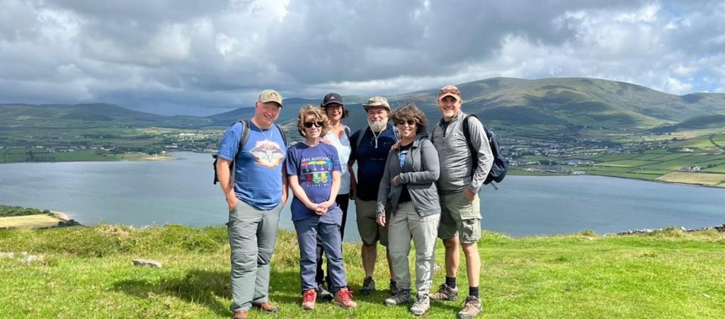 Group of hikers posing with scenic hills and a body of water in the background.