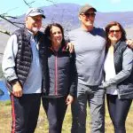 Four people are standing together outdoors, dressed casually, with a scenic background of Ireland's mountains, greenery, and a lake. They appear happy and are posing for the camera. Looks like they just finished an Active Tour!