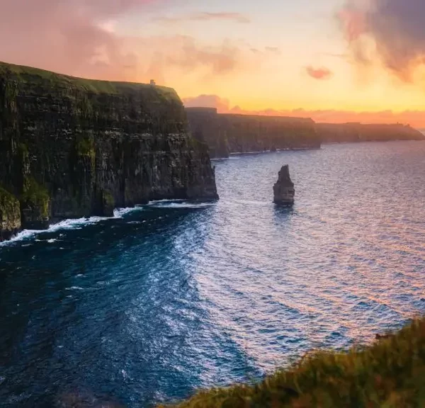 Sunset illuminates the cliffs of moher and the atlantic ocean, highlighting their rugged beauty under a dramatic sky.