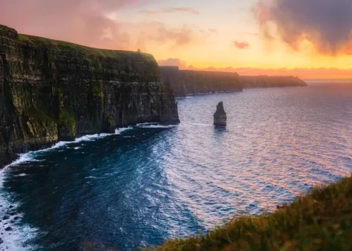 Sunset illuminates the cliffs of moher and the atlantic ocean, highlighting their rugged beauty under a dramatic sky.